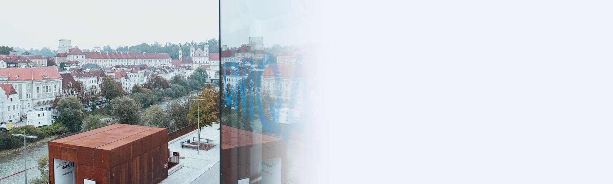 Blick auf die Altstadt von Steyr mit der Enns im Vordergrund und dem UNIQA-Schriftzug auf einer Glasfassade der Generaöagentur Team Steyr